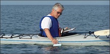 John Schott measures water temperature from a kayak.