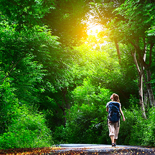 Young woman walking on green asphalt road in forest
