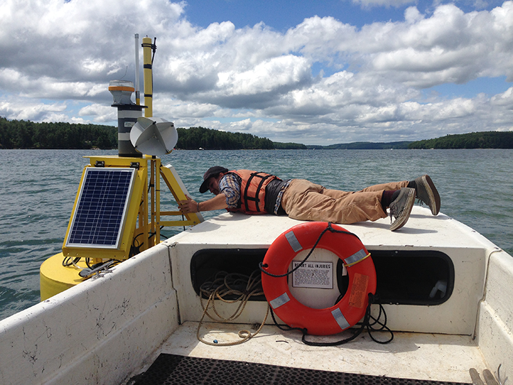 Tom Kiffney, an undergraduate intern, ties off to a buoy in the Damariscotta River, Maine