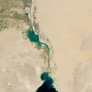 Circles of green on the image top left give way to turquoise blue waters in the image center that is connected by a blue line of a canal to a darker blue body of water at the image bottom center. Image shows an area near Sadat City in Egypt.