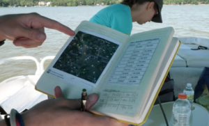 Wake Forest student holds a data notebook while on a boat showing water sample points.