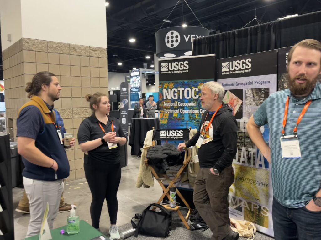 Landsat Outreach team member, Allison Nussbaum (second from the left), communicates with USGS National Geospatial Technical Operations Center (NGTOC) team members at the Geo Week USGS booth.