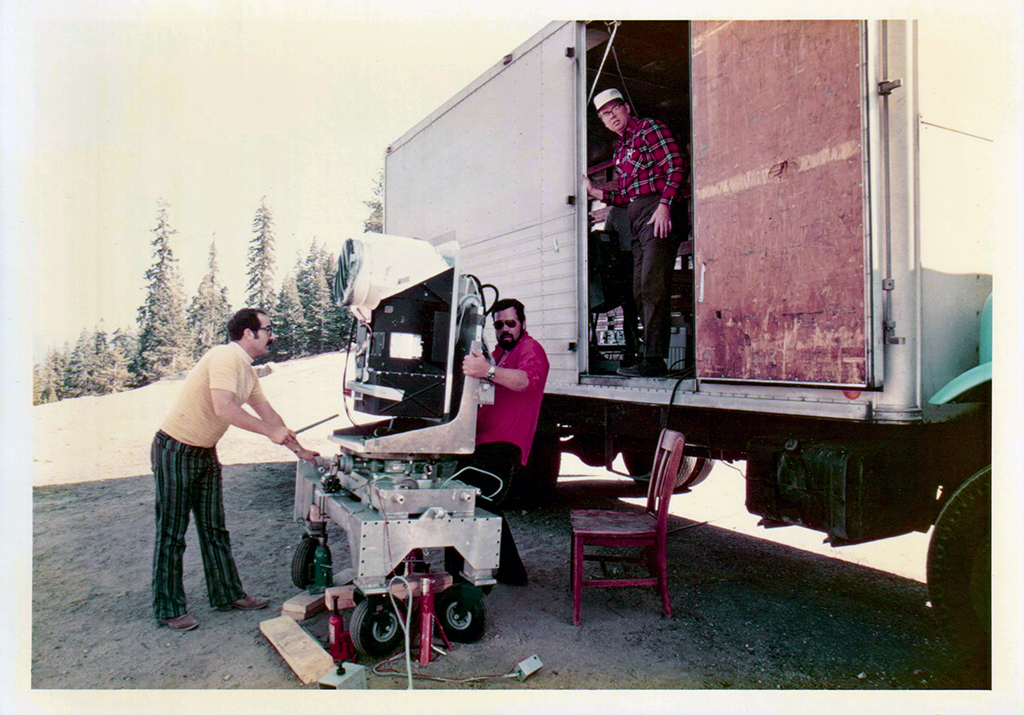 Two men move the MSS engineering model. A technician stands on the truck wearing a red shirt.