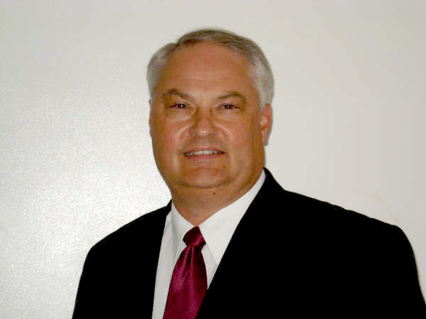 Headshot of Tony Willardson. he is wearing a black suit jacket, dark red tie, and white shirt.