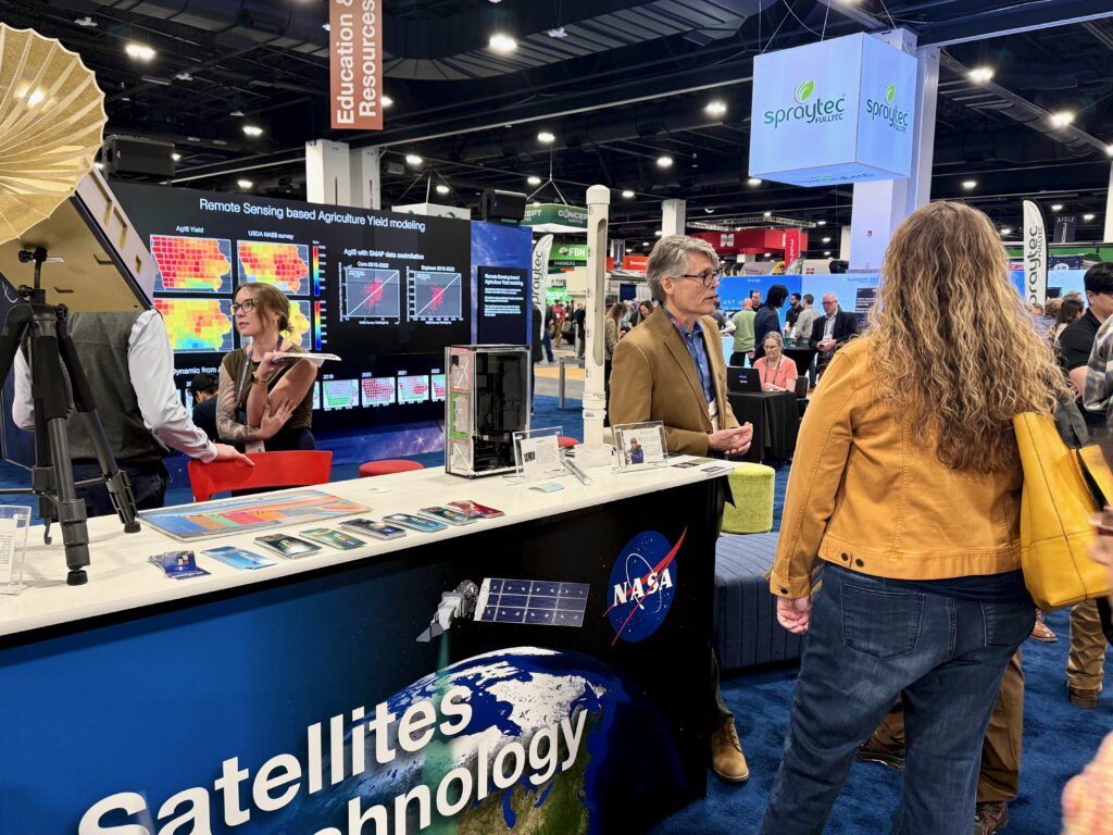 Attendees interacting with NASA scientists at a booth