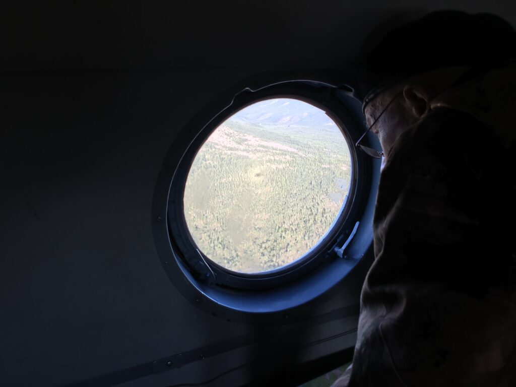 Researcher looking out of the window while flying over the boreal forests.