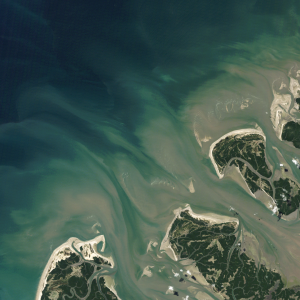 A Landsat satellite image featuring tan and green shallow water contrasted with the dark blue ocean
