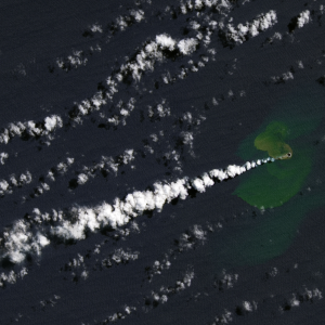 A Landsat satellite image featuring a faint green island with puffy white smoke pouring out across the image